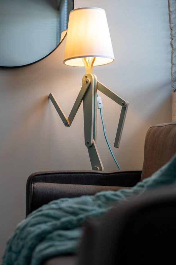 Una lámpara de diseño original que recuerda a una figura humana, sobre una mesa.