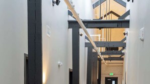 A long, narrow hallway with white walls, black structural columns, and a polished concrete floor.