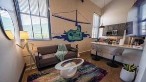 A modern living room with a sofa, a unique glass-top coffee table, and a colorful rug.