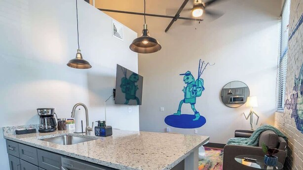 A modern kitchen with a large island, stainless steel appliances, and pendant lighting.