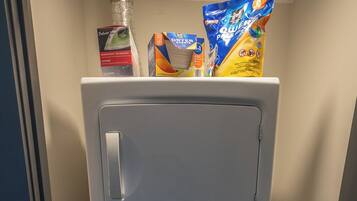 A compact, grey portable washer-dryer unit with a front-loading door, control panel with multiple settings, and a small storage compartment.