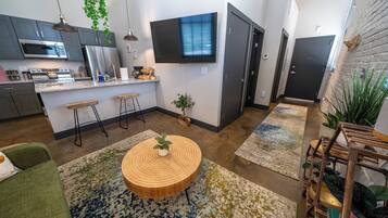 A modern kitchen with stainless steel appliances, a flat-screen TV, and a dining area with a round wooden table.