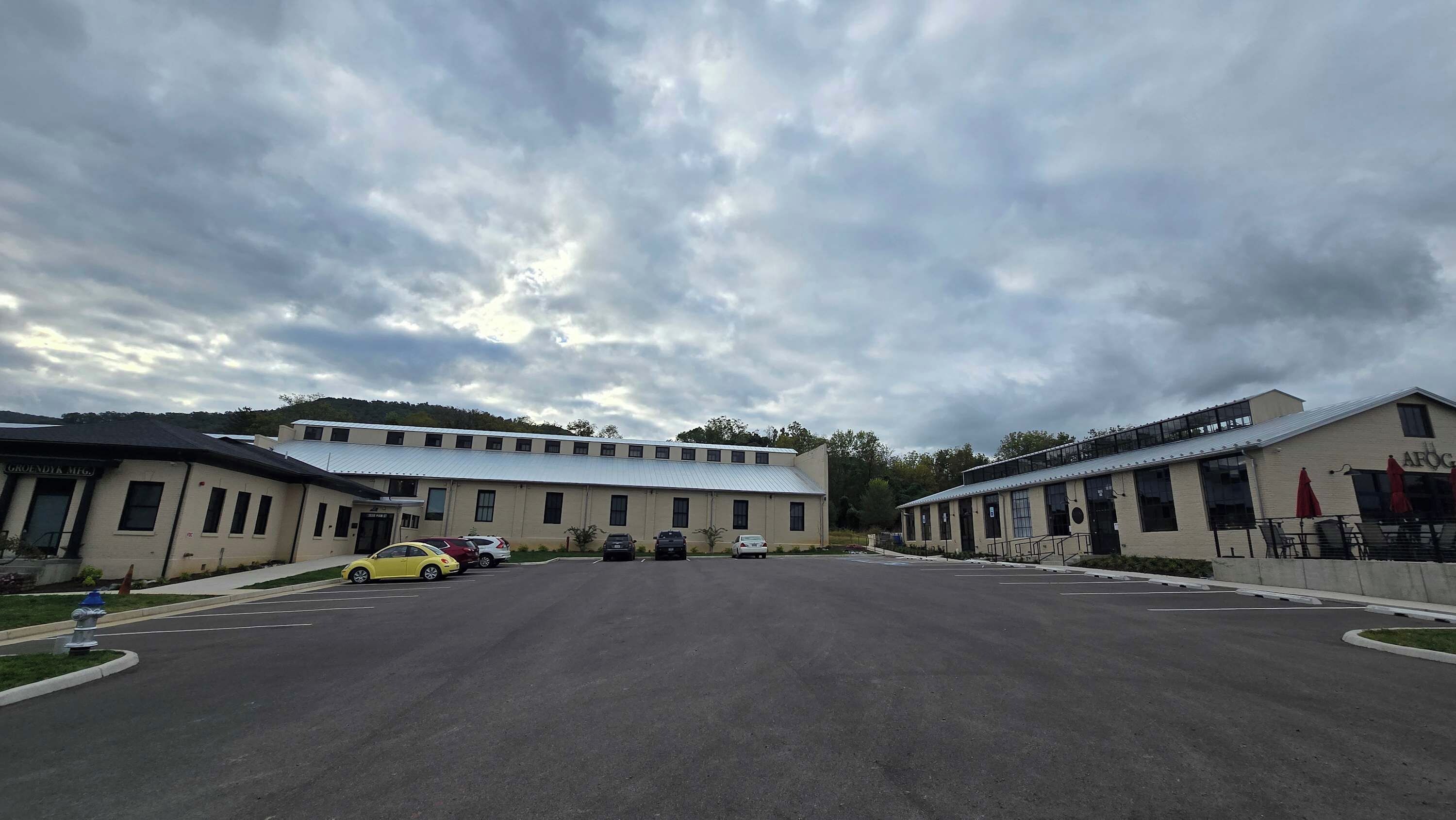 A parking lot with several cars and a building with a flat roof and multiple windows.