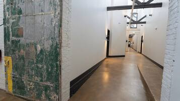 A corridor with white brick walls and a concrete floor, leading to a staircase.