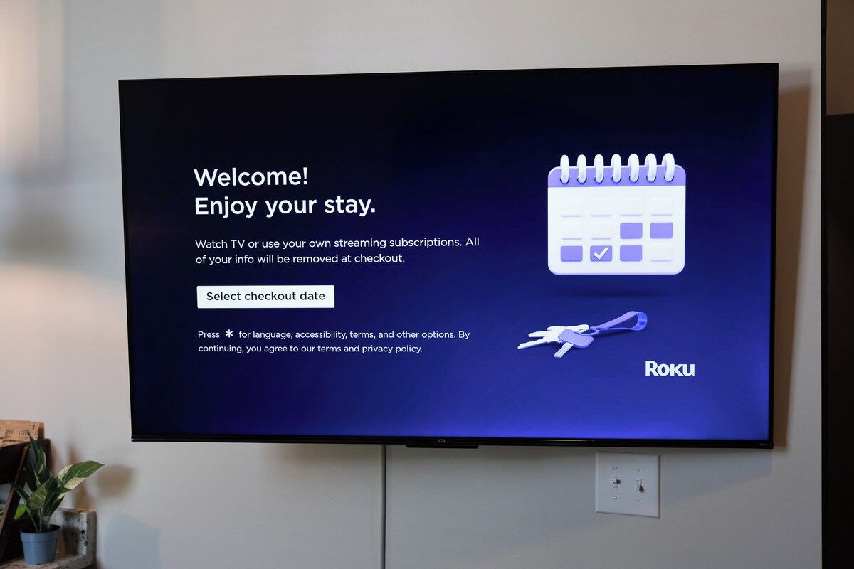 A television screen displaying a welcome message for Roku, with options to select a checkout date and language settings.