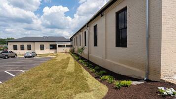 A building with a parking lot, a grassy area, and a row of windows.