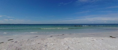 Une plage de sable blanc aux eaux turquoise et calmes.