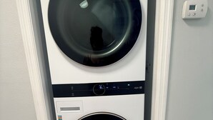 Une machine à laver et un sèche-linge superposés, installés dans un couloir.