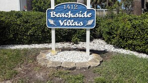 Un panneau indiquant « Beachside Villas, numéro 1412 », entouré de verdure et de palmiers.