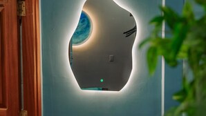 A wall-mounted air conditioning unit with a unique design, a wooden door frame, and a plant in the foreground. - Sora Home - your private sky (Ho Chi Minh City)