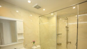 A modern bathroom with a glass-enclosed shower, a white sink, and a toilet. - Sora Home - your private sky (Ho Chi Minh City)
