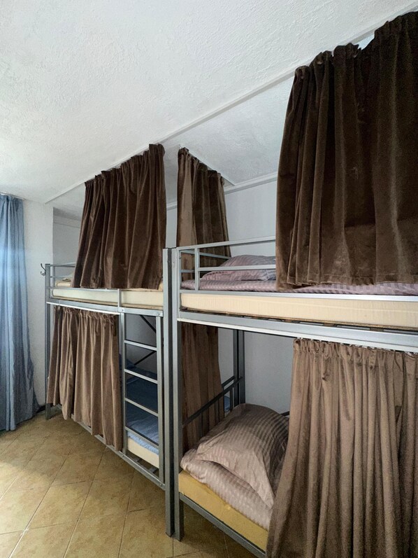 A dormitory room with bunk beds, each covered with brown curtains. - Rooms Tolebi. (Almaty)