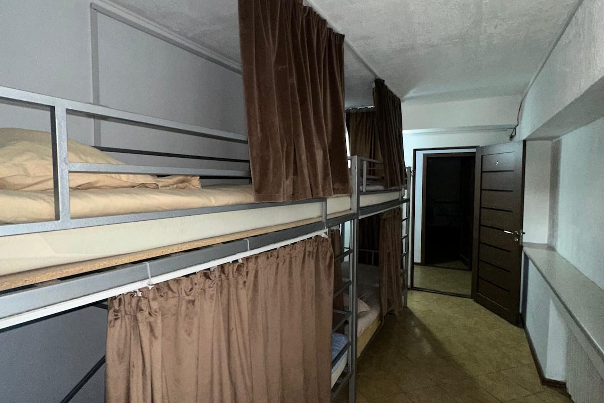 A dormitory room with bunk beds, a door, and a tiled floor.