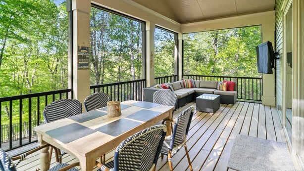 A covered outdoor deck with a dining table, chairs, and a sofa. - Cozy Lakefront Getaway with Dock, Fire Pit, hot tub & Screened Porch (Catawba)