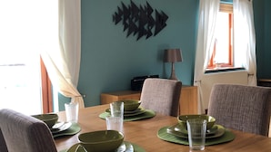 A dining area with a wooden table set for four, green placemats, and matching bowls. - Marina Waterfront Apartment - family & pet-friendly near to pubs & beach (Milford Haven)