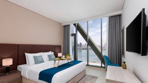 A modern hotel room with a large bed, a desk, and a TV.