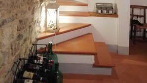 A stone-walled room with a wooden staircase leading to a higher level.