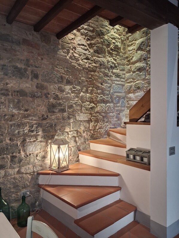 A staircase with stone walls and a lantern on the landing.