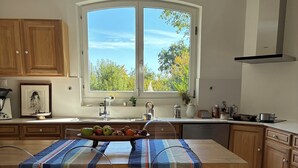A modern kitchen with a large island, clear chairs, and a view of trees through a window. - 4 rooms in a renovated eco house in a quiet natural setting (Sarreguemines)