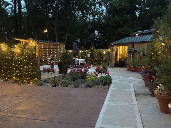 Eine Terrasse mit Lichterketten, Topfpflanzen und einer Sitzgelegenheit.