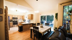 A modern kitchen with wooden cabinets, a microwave, and a dining area with a table and chairs. - Heated Swim Spa + Outdoor Movie Theater, Private Resort (Kansas City)