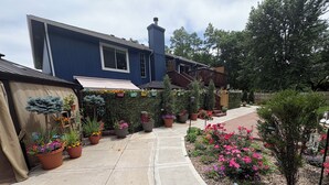 A blue house with a garden pathway, potted plants, and a welcome sign. - Heated Swim Spa + Outdoor Movie Theater, Private Resort (Kansas City)