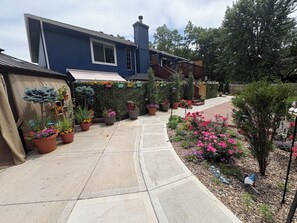 A blue house with a garden pathway, potted plants, and a welcome sign.