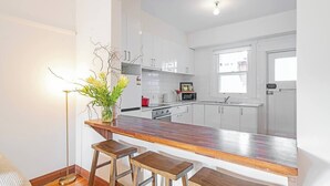 A modern kitchen with white cabinets, a wooden countertop, and bar stools.