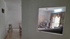 Un salon comprenant un canapé, un fauteuil et un coin repas avec une table et des chaises.