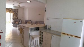 Une cuisine équipée d’un réfrigérateur, d’un évier et d’un coin repas avec des chaises et une table.
