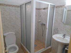 A bathroom with a toilet, a shower enclosure, and a sink.