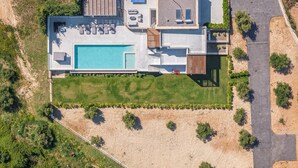 An aerial view of a modern house with a swimming pool, outdoor seating, and a garage. - Skyline Villa II, By Hellocrete (Aggeliana)