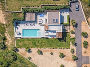 An aerial view of a modern house with a swimming pool, outdoor seating, and a garage.