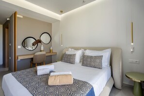 Une chambre dâhĂŽtel moderne avec un grand lit, un bureau, une chaise, un miroir rond et une petite table ronde.