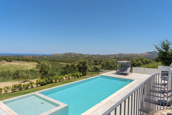 Una piscina rectangular con agua cristalina y azul, rodeada por una valla baja y un área de descanso cubierta con una silla y una mesa.