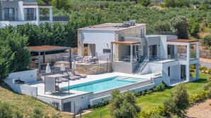 A modern villa with a swimming pool, outdoor seating, and a view of the surrounding landscape. - Skyline Villa II, By Hellocrete (Aggeliana)
