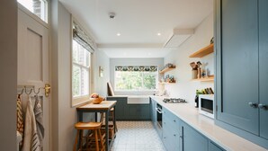 A compact kitchen with a window, a sink, and wooden stools. - Cleve Cottage by inspirestays.com - a cottage that sleeps 4 guests in 2 bedrooms (Lewes)