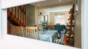 A dining area with a table set for four, wooden chairs, and a vase with flowers. - Cleve Cottage by inspirestays.com - a cottage that sleeps 4 guests in 2 bedrooms (Lewes)