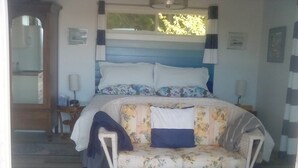 A bedroom with a bed, a sofa, a mirror, and a window. - Cloud 9 roof top studio in Maderia Park is waiting for your enjoyment. (Madeira Park)