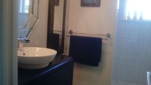 A bathroom with a white sink, dark countertop, and a towel rack with a dark towel. - Cloud 9 roof top studio in Maderia Park is waiting for your enjoyment. (Madeira Park)