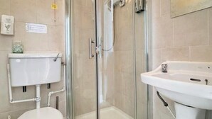 A bathroom with a glass-enclosed shower, a white toilet, and a sink. - Kendal Hotel (Blackpool)