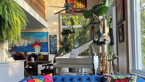 Une pièce avec un canapé bleu, un piano et diverses œuvres d’art.