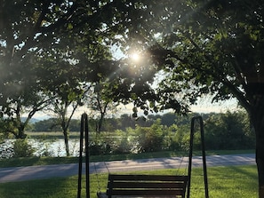 Un banc de parc, à l'ombre d'un arbre, où la lumière du soleil filtre à travers les feuilles.