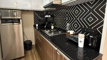 Een moderne keuken met een magnetron, fornuis en een zwart aanrecht achterwand.