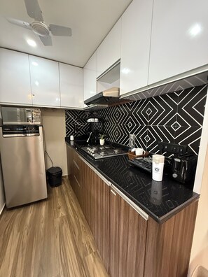 A modern kitchen with a microwave, stove, and black countertop backsplash.
