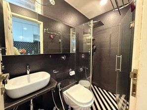 Un baño con lavamanos blanco, inodoro, ducha y espejo.