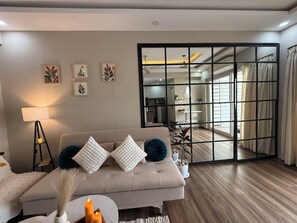 Un salon moderne avec un canapé, une lampe et des œuvres d’art accrochées au mur.