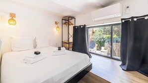 Een hotelkamer met een bed, een kledingkast, een raam met gordijnen en een airconditioning.