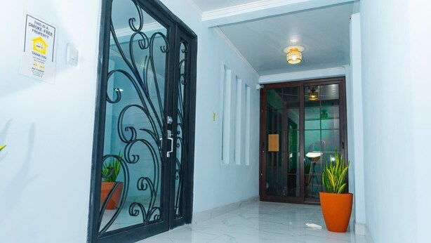 A hallway with a black metal gate, a potted plant, and a sign indicating the property is smoke-free.