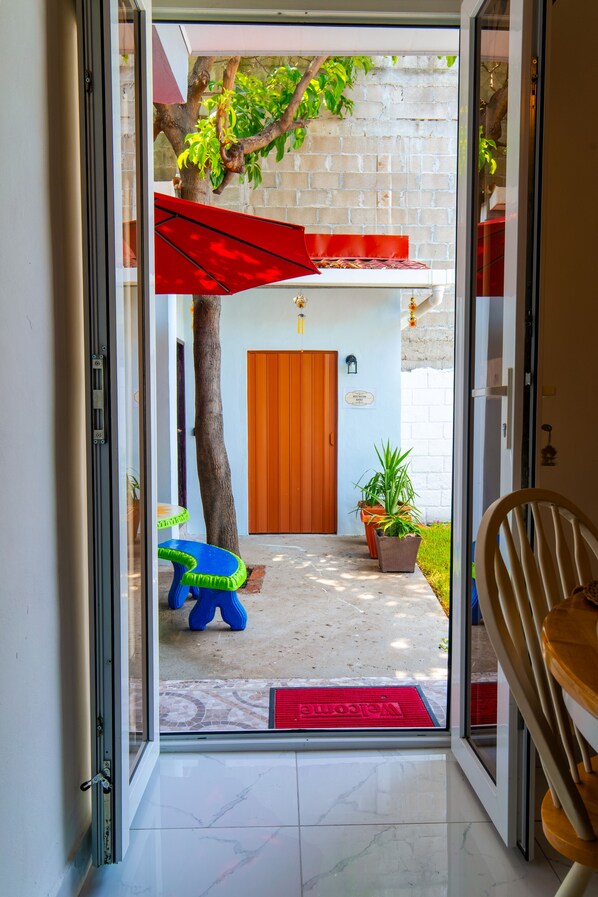 Una entrada de hotel con piso de baldosas, puerta de madera, un paraguas rojo y un felpudo.